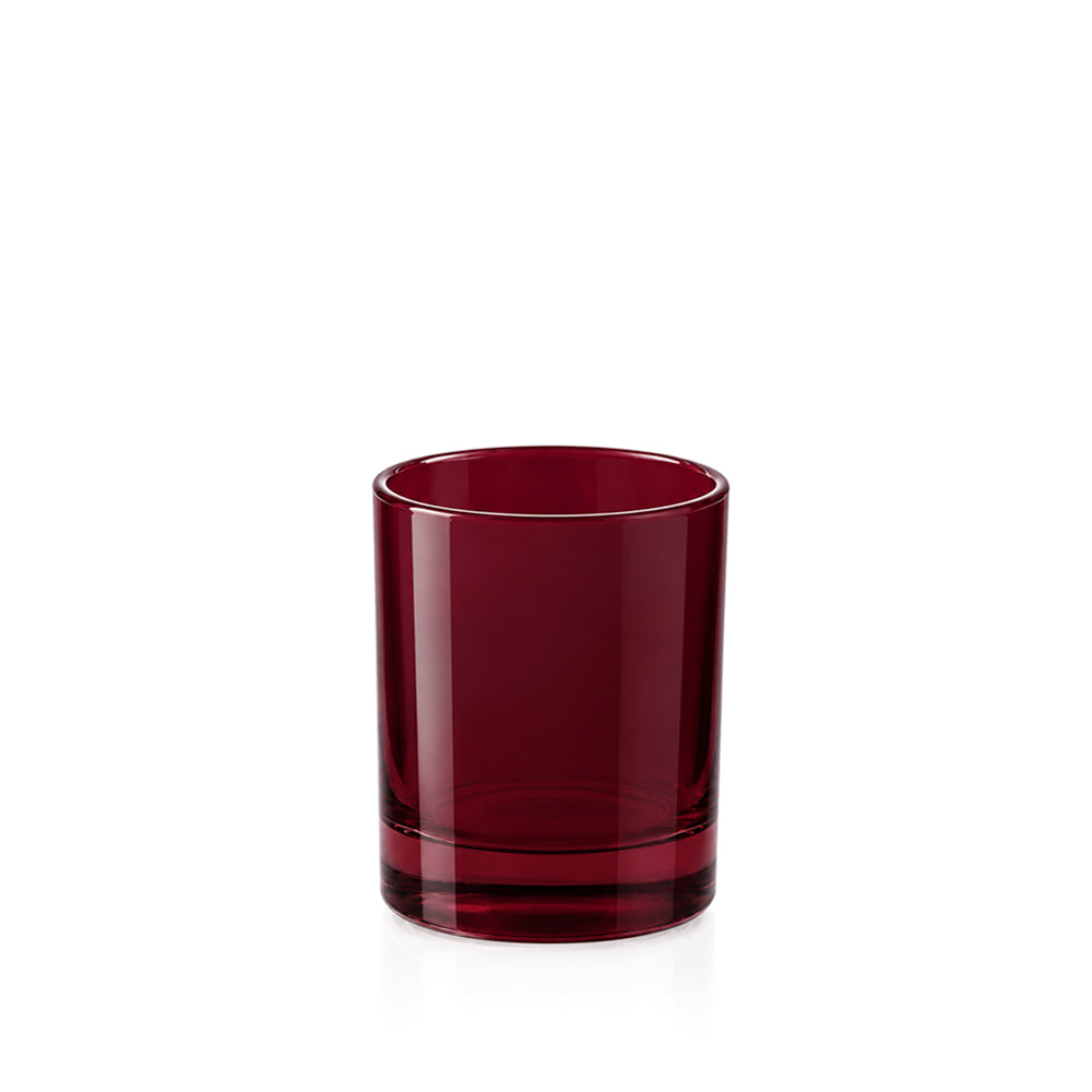 A single dark red translucent glass tumbler with a thick base, photographed on a clean white background.